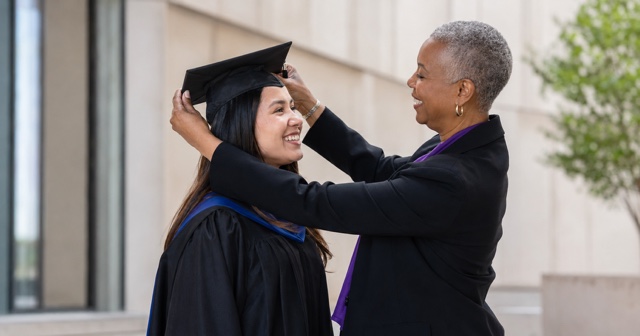 A mentor placing a graduation cap on a smiling graduate