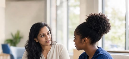 A mentor in conversation with her mentee at a table