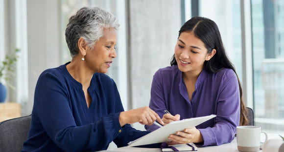 A mentor and mentee reviewing notes together at a table